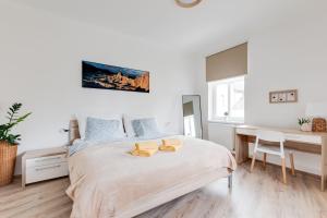 a white bedroom with a bed and a desk at Modern, bright and spacious apartment in Prague