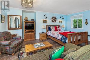 a bedroom with a bed and a living room at Salty Towers Ocean Front Cottages in Sooke