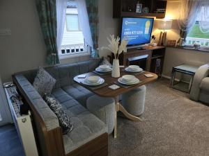een woonkamer met een bank, een tafel en een televisie bij Rosie's Seton Retreat in Port Seton