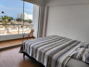 1 dormitorio con cama y ventana grande en SAN BARTOLO BEACH BUILDING, en San Bartolo