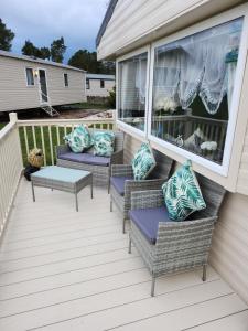 een veranda met rieten stoelen en kussens erop bij Rosie's Seton Retreat in Port Seton