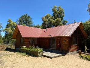 una pequeña casa de madera con techo rojo en Camping y Cabañas Playa Caliboro, en Los Ángeles