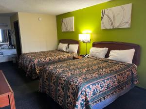 Dos camas en una habitación de hotel con paredes verdes. en Lebanon Inn Motel, en Lebanon