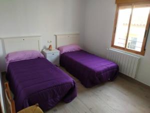 2 camas en una habitación con sábanas moradas en Vivienda turística Ca Lola, en Vilafamés