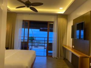 a bedroom with a bed and a television and a balcony at Woody's Place Siargao in General Luna