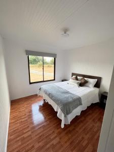 Habitación blanca con cama y ventana en Cabañas Los Naranjos - Lanco, en Lanco