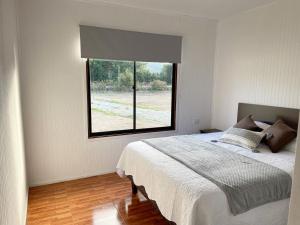 a bedroom with a bed and a large window at Cabañas Los Naranjos - Lanco in Lanco