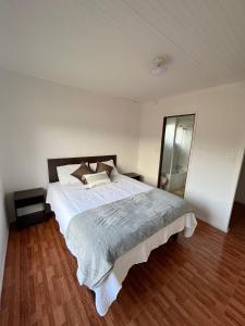 1 dormitorio con 1 cama grande y suelo de madera en Cabañas Los Naranjos - Lanco, en Lanco