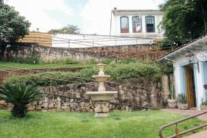 una fontana nell'erba di fronte a un muro di pietra di Pousada Relicário a Tiradentes
