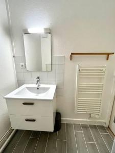 ein Badezimmer mit einem weißen Waschbecken und einem Spiegel in der Unterkunft Khara - SILS in Caen