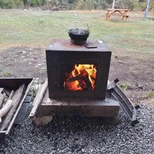 un horno de fuego con una olla encima en Hostal del río en El Bolsón