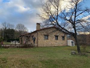 an old stone house in a field with a tree at Casa Rural Fuentecillas in Becedas