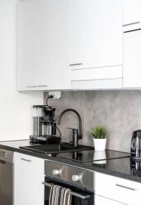 a kitchen with white cabinets and a stove top oven at Apartment near the train station, free parking &Netflix in Kuopio
