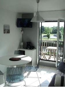 a kitchen with a table and chairs and a balcony at 2 pièces ensoleillé accès direct plage in Cabourg