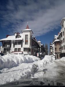 a snow covered street with a building and buildings at APARTAMENT-DAMO in Pamporovo