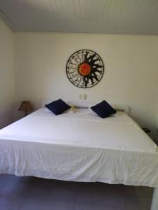 a bedroom with a white bed with a clock on the wall at El Campo in Savegre