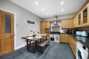 a kitchen with wooden cabinets and a table in it at Huge House, Near Rugby Stadium, Pool Table, Parking, Garden in Gloucester