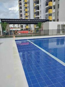 - une piscine avec du carrelage bleu et des bâtiments dans l'établissement APARATAMENTO DE DESCANSO EN GIRARDOT, à Girardot