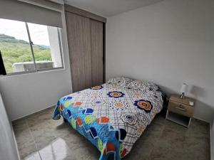- une chambre avec un lit doté d'une couette colorée et d'une fenêtre dans l'établissement APARATAMENTO DE DESCANSO EN GIRARDOT, à Girardot