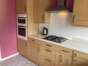 a kitchen with wooden cabinets and a stove top oven at bungalow on the south coast & new forest in Lymington