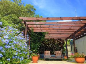 a wooden pergola with two benches and some flowers at Selwyn Cottage in Burnt Pine