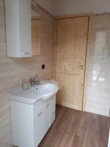 a bathroom with a white sink and a wooden door at Casa Ylenia in Borzonasca +61 photos