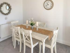 a dining room table with white chairs and a clock at Panorama Apartment 1 - Uk40626 in Southbourne