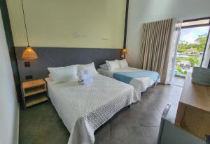 Habitación de hotel con 2 camas y ventana en Hotel Capri Doradal en Doradal