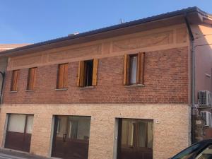 Appartamento civico 14 في Campoformido: مبنى من الطوب عليه نوافذ ساترة