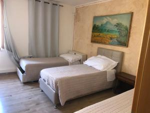 Appartamento civico 14 في Campoformido: غرفة بسريرين ولوحة على الحائط