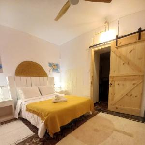 um quarto com uma cama com um cobertor amarelo e uma porta em Guesthouse Jazmínes Mozárabes # WIFI em Baena