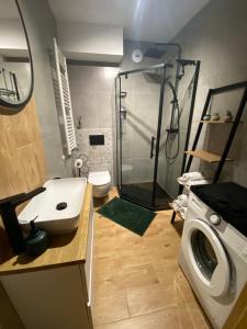 a bathroom with a shower and a sink and a washing machine at Apartament Spokojna Przystań in Rzeszów