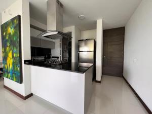 a kitchen with a black counter and a refrigerator at Super apartamento en club residencial in Pereira