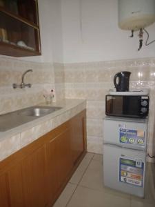 eine Küche mit einer Spüle und einer Mikrowelle in der Unterkunft Hôtel Résidence Georges Colette in Yopougon