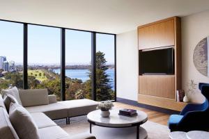 a living room with a tv and large windows at The Ritz-Carlton, Perth in Perth