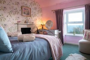 a bedroom with a bed with a fireplace and a window at Alma's Cottage at Penmaenmawr in Penmaen-mawr