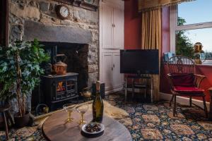 sala de estar con mesa con copas de vino y chimenea en Alma's Cottage at Penmaenmawr, en Penmaen-mawr