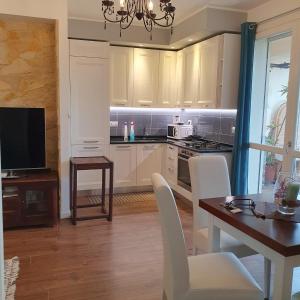 a kitchen with white cabinets and a table with chairs at Giancasavacanze in Alghero