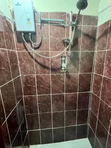 y baño con ducha y azulejos marrones. en Hospedaje Rumiñahui, en Ollantaytambo