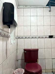 baño con aseo rojo y TV en Hospedaje Rumiñahui, en Ollantaytambo