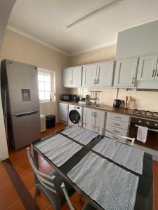 a kitchen with a table and a stainless steel refrigerator at Apartamento Vicentino in Vila Nova de Milfontes