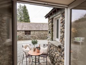 a patio with a table and chairs outside a window at Hart Head Barn in Ambleside