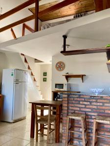 a kitchen with a table and a refrigerator at Villas da Jagua in Jaguaruna