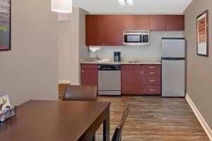 a kitchen with a table and a refrigerator and cabinets at TownePlace Suites by Marriott Albany Downtown/Medical Center in Albany