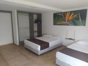 - une chambre avec 2 lits et un tableau mural dans l'établissement Hotel Las Aldeas, à Montenegro
