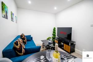 a living room with a blue couch and a tv at WEEKLY & MONTHLY STAY - Beautiful 2 Bed House with FREE Parking - Relocation, Business & Group - 5 Guests - By Den Accommodation Short Lets & Serviced Accommodation, Woolwich in Woolwich