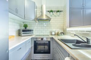 Una cocina blanca con fregadero y microondas. en Basilica View Apartment, en Budapest
