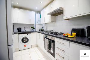 a kitchen with white cabinets and a washer and dryer at WEEKLY & MONTHLY STAY - Beautiful 2 Bed House with FREE Parking - Relocation, Business & Group - 5 Guests - By Den Accommodation Short Lets & Serviced Accommodation, Woolwich in Woolwich +18 photos