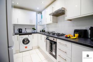 a kitchen with white cabinets and a washer and dryer at WEEKLY & MONTHLY STAY - Beautiful 2 Bed House with FREE Parking - Relocation, Business & Group - 5 Guests - By Den Accommodation Short Lets & Serviced Accommodation, Woolwich in Woolwich