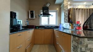Luxurious studio apartment in Newtown في Thākurdwari: مطبخ مع دواليب خشبية ونافذة